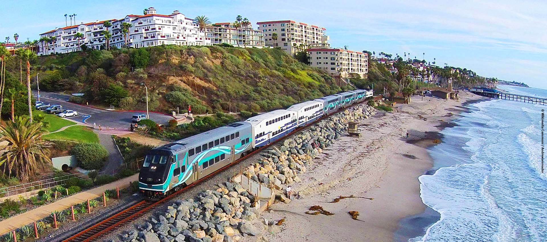 Los Angeles Metrolink train rolling on tracks beside the beach. 